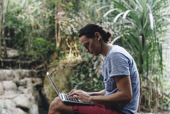 White man using computer laptop at waterfall